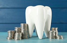 A large model tooth surrounded by stacks of silver coins
