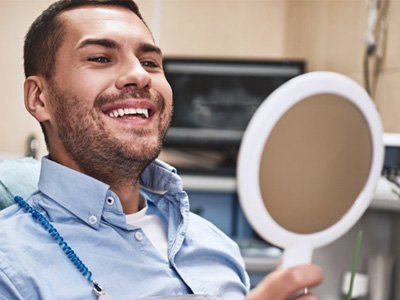 a dental patient checking his smile with a mirror