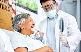 Woman smiling at reflection in handheld mirror