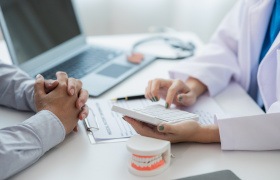 Dentist using calculator in office with patient