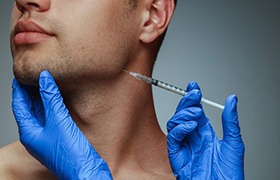 Man receiving a dermal filler injection near his jawline
