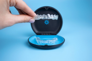 Hand lifting up Invisalign tray from its case